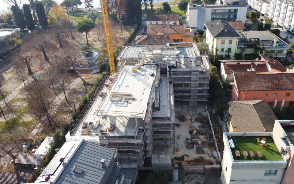 Cantiere edile tra edifici residenziali con gru e impalcature.