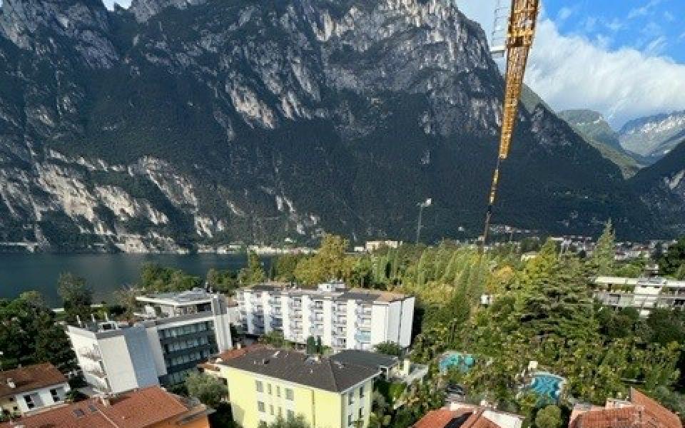 Vista di un cantiere edile con montagne e lago sullo sfondo.