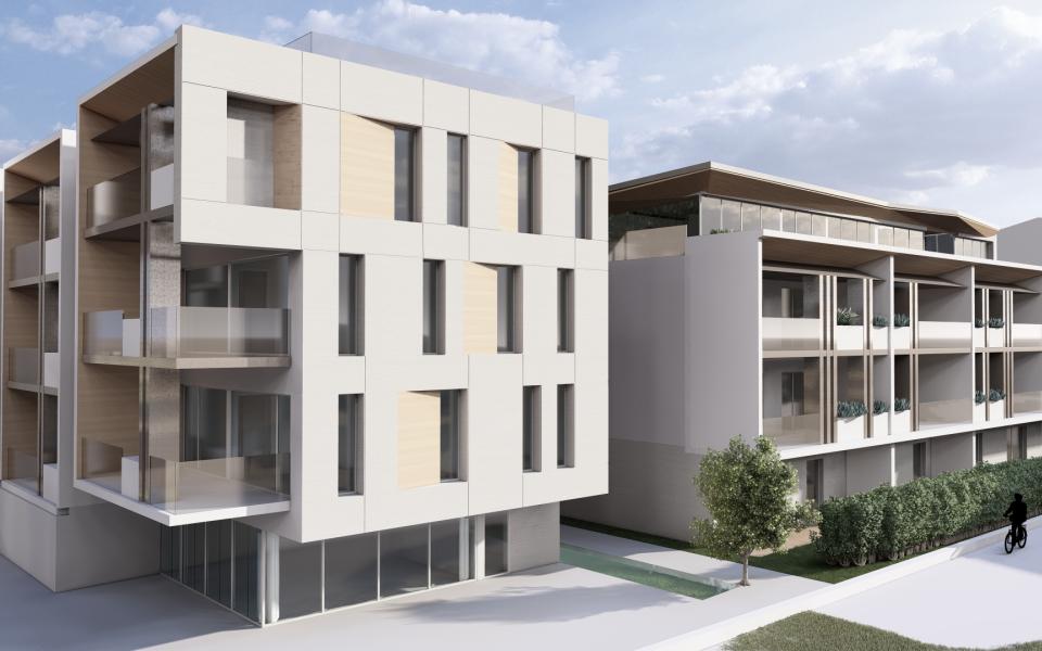 Edifici moderni con balconi e ampie finestre, circondati da vegetazione.